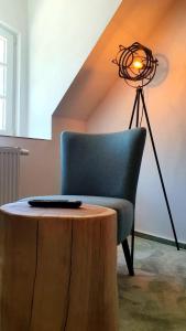 a room with a chair and a table and a lamp at Hotel Le Filou in Hille