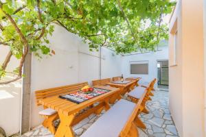 una fila de mesas y sillas de madera bajo un árbol en Guest House Edita, en Ulcinj