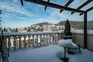 uma varanda nevada com uma cadeira e uma árvore de Natal em Hotel Litovel em Luhačovice