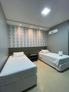 um quarto com 2 camas e uma janela em Hotel Mandino em Lucas do Rio Verde