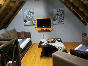 a living room with a tv and two zebras on the wall at African Sky in Marloth Park