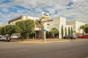 un grand bâtiment blanc avec des voitures garées dans un parking dans l'établissement Hotel Mandino, à Lucas do Rio Verde