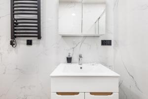 a white bathroom with a sink and a mirror at Bm apartamenty Wały Chrobrego Radogoska12A in Szczecin