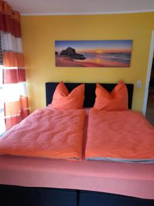 a bed with two orange pillows on it at Ferienwohnungen am Moselbeach in Mehring
