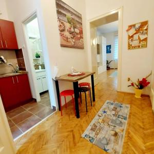 a kitchen and dining room with a table and red chairs at Apartment TRio in Novi Sad