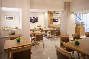 a restaurant with tables and chairs and a tv at Hotel Hermes in Rhodes Town