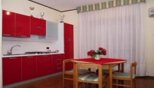 uma cozinha com armários vermelhos e uma mesa com flores em Residence Royal em Siracusa