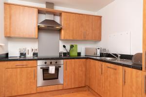 a kitchen with wooden cabinets and a stove top oven at Oakstays Stylish Quayside Gem in Gateshead