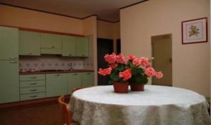 - une cuisine avec une table ornée de fleurs roses dans l'établissement Residence Royal, à Syracuse