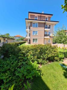 a tall apartment building with a green yard at Villa Yanevi in Ravda