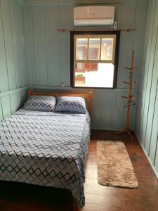 a small bedroom with a bed and a window at CASA TREIN - há 20 minutos do centro de Gramado in Três Coroas
