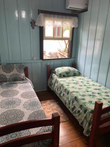 a bedroom with two beds and a window at CASA TREIN - há 20 minutos do centro de Gramado in Três Coroas