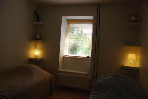 a bedroom with a window and two beds and two lights at Quistgaarden Bed & Breakfast in Spjellerup