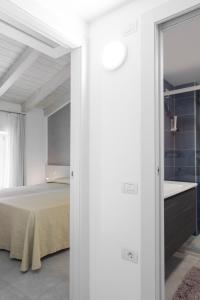 a white bedroom with a bed and a bathroom at Appartamento Campagnola Mansardato in Riva del Garda