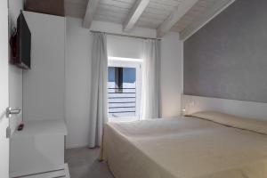 a white bedroom with a bed and a window at Appartamento Campagnola Mansardato in Riva del Garda