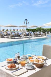 een tafel met eten naast een zwembad bij Hotel Cavalieri Palace in Lido di Jesolo