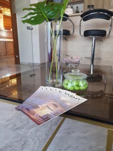 une table avec un magazine, un vase et quelques pommes dans l'établissement Varmy, à Ierápetra