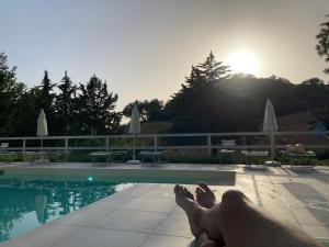 a person laying on the edge of a swimming pool at VILLA DEGLI ARCHI B&B - Ristorante in Castorano