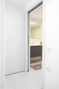 a white bathroom with a sink and a mirror at Appartamento Campagnola Mansardato con soppalco in Riva del Garda