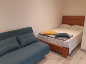 1 dormitorio pequeño con 1 cama y 1 sofá en Logement proche Lyon-aéroport-Centrale Bugey, en Dagneux
