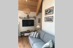 uma sala de estar com um sofá azul e uma televisão de ecrã plano em Magnifique appartement à la Joue du Loup em Le Dévoluy