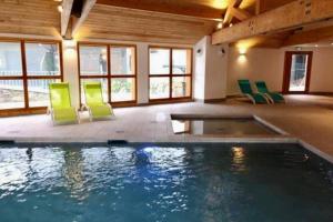 una piscina en una casa con sillas verdes en Magnifique appartement à la Joue du Loup en Saint-Étienne-en-Dévoluy