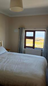 Un dormitorio con una cama grande y una ventana en Lios Éinne House Accommodation, en Inis Oírr