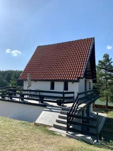 ein Haus mit rotem Dach und Treppen neben einem Teich in der Unterkunft NG Apartmani Tornik Zlatibor in Zlatibor