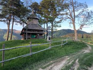 eine kleine Hütte auf einem Hügel mit einem Zaun in der Unterkunft Біля Ріки in Mischhirja