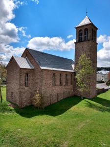 eine alte Backsteinkirche mit einem Turm auf einem Feld in der Unterkunft Ferienwohnung Paula in Oberhof