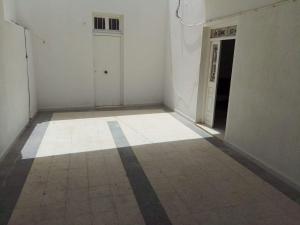 een lege kamer met een deur en een tegelvloer bij S+2 Beltaief Residence in Houmt Souk