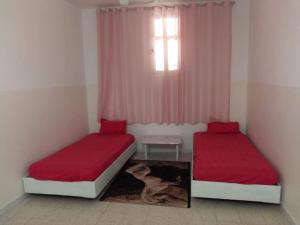 een slaapkamer met 2 bedden met rode lakens en een raam bij S+2 Beltaief Residence in Houmt Souk