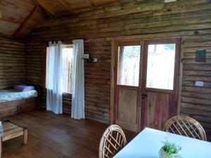 Habitación con mesa y sillas en una cabaña de madera en Cabañas Artemisa en Tandil