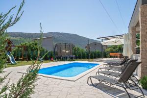 einen Pool mit zwei Stühlen und einem Spielplatz in der Unterkunft Villa Naklice in Omiš