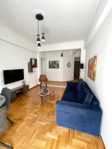 a living room with a blue couch and a tv at Kallimarmaro 2-Bedroom Apartment in Athens