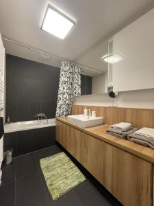W łazience znajduje się umywalka, wanna i lustro. w obiekcie Modern Danube Apartment Vienna w Wiedniu