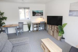 a living room with a couch and a tv and a table at ChiPad Mono - Comfy City Centre Apartment with Free Parking Space in Chichester