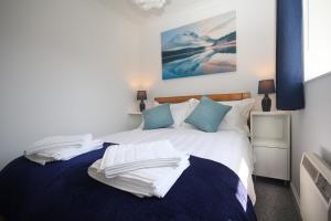 a bedroom with a bed with white sheets and blue pillows at ChiPad Mono - Comfy City Centre Apartment with Free Parking Space in Chichester