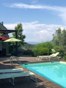 a swimming pool with two lawn chairs and an umbrella at Casa do Eido dos Calhões in Ponte de Lima