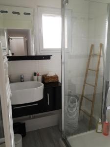 La salle de bains est pourvue d'un lavabo blanc et d'une douche. dans l'établissement Les baigneurs, à Merville-Franceville-Plage