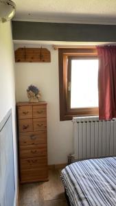 Un dormitorio con una cama y una cómoda y una ventana. en Be Smiling Apartment, en Passo del Tonale