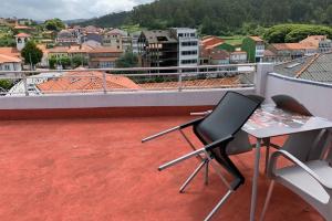 einen Balkon mit einem Tisch und Stühlen auf dem Dach in der Unterkunft Duplex con terraza in Ponte Do Porto