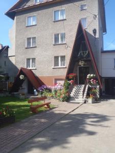 a building with a bench and flowers in front of it at Apartamenty Bogusia Korbielów Pilsko in Korbielów