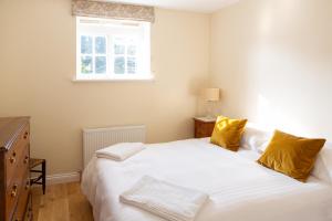 Henley Hall, Ludlow في لودلو: غرفة نوم بسرير ابيض كبير مع مخدات صفراء