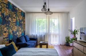 a bedroom with a blue couch and a large window at Secret Garden Apartman in Miskolc