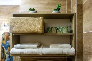 - une étagère avec des serviettes et des plantes dans la salle de bains dans l'établissement Secret Garden Apartman, à Miskolc
