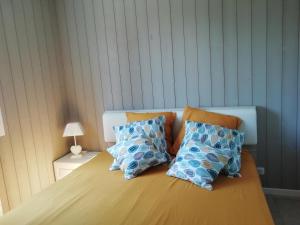 Una cama con almohadas azules y naranjas. en La Maison de Joindy en Saint-Cyprien