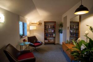 ein Wohnzimmer mit 2 Stühlen, einem Tisch und Bücherregalen in der Unterkunft Pension Kirschberg in Bretleben