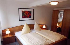 a bedroom with a white bed with two lamps at Hotel garni am Thüringer KloßTheater in Friedrichroda