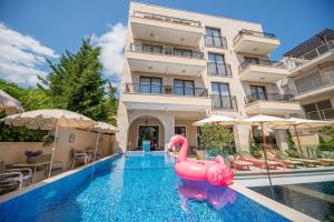 a swimming pool with a pink flamingo in front of a building at B&B Amfora in Petrovac na Moru